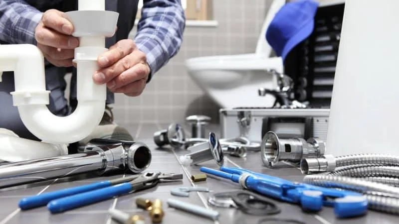 Hands working on sink plumbing with tools